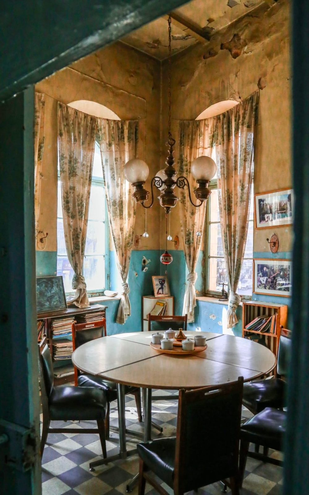 Interior of a traditional tea house in Jabal Al Weibdeh, with vintage décor, tall curtained windows, and a round table set for tea