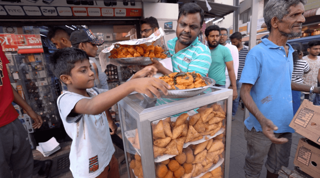 Street Food being sold at a public market in Colombo, Sri Lanka surrounded by an audience