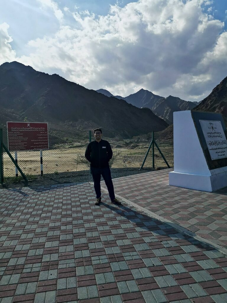 Tarun Krishna smiling with the mountains behind him and a fence covering the Sadah Dam