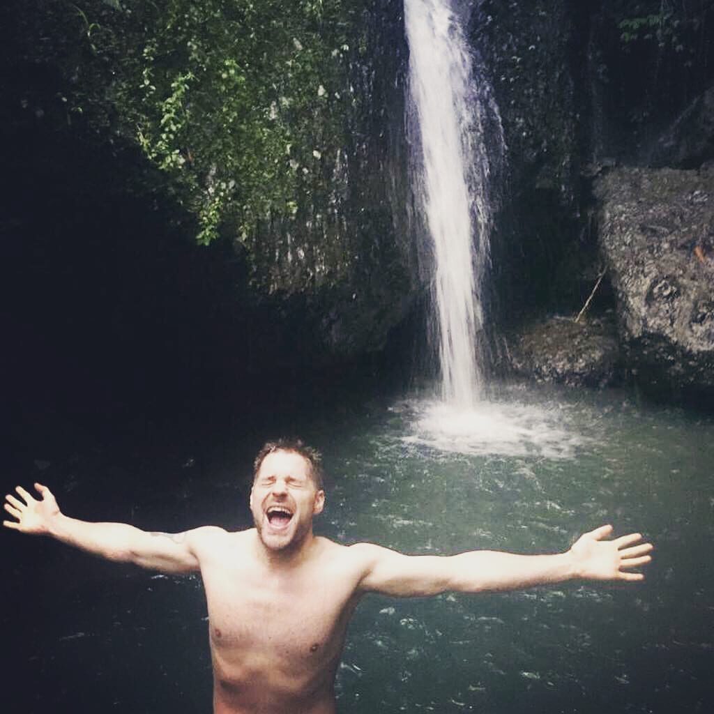 Eivind from Norway Couch surfing is posing celebratory near a waterfall in Java, Indonesia