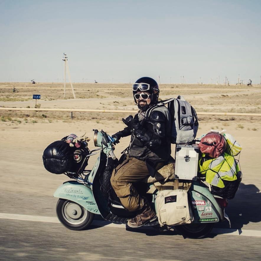 Markus Mayer standing with his vespa posing with a desert background