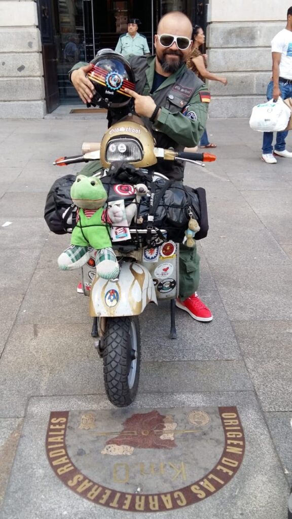 Markus Meyer posing with his helmet in his hands while sitting on his vespa